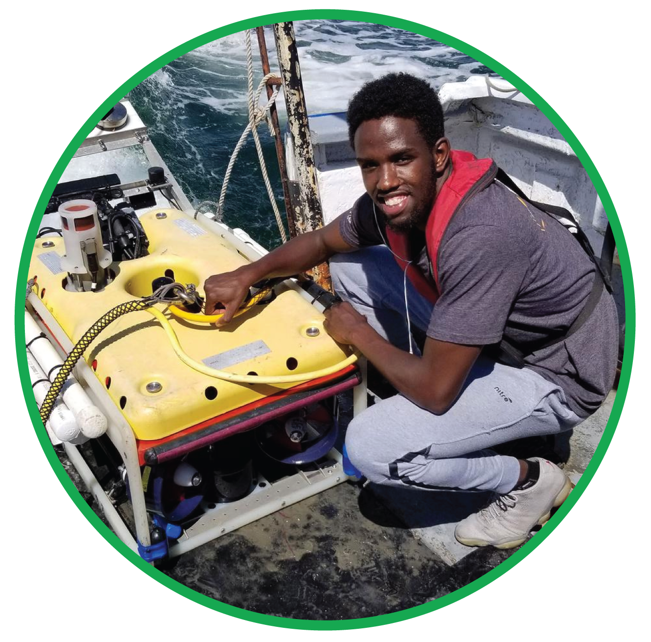 A student working on a research vessel adjusting the hose to an underwater submersible